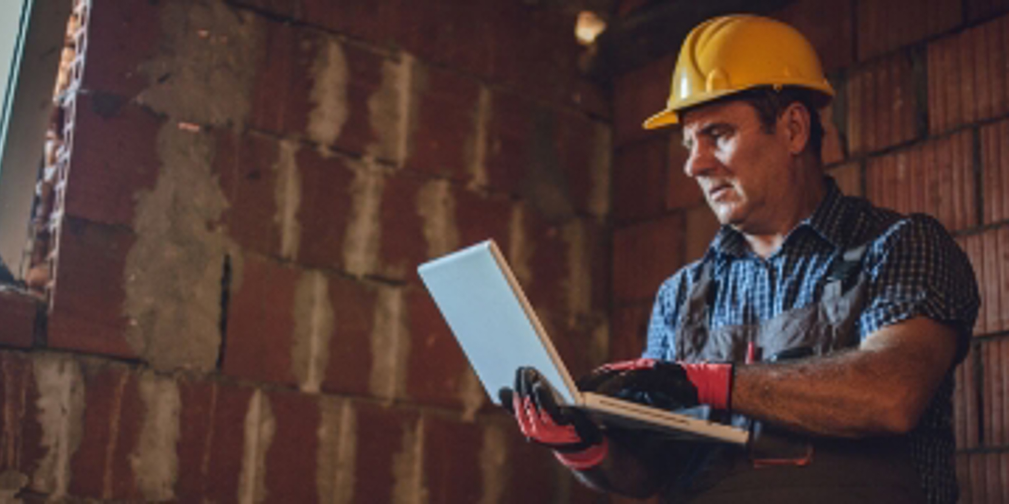 Man met laptop in de bouw